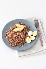 Buckwheat porridge on a plate with quail eggs and two slices of butter. Healthy food concept. Copy space.