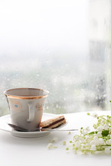 cup of tea near window with raindrops 