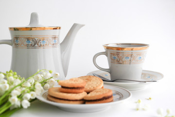 Teacup, teapot and cookies on the white table 