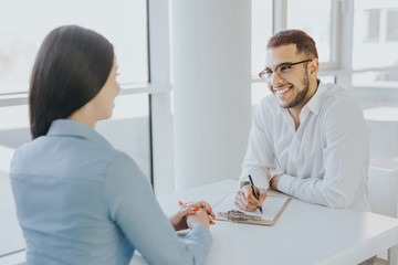 Fototapeta premium Smiling colleagues working on a project together in an open space area of an international office