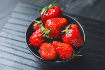 Bowl with ripe strawberry on dark background