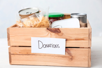 Box with donations on table against light background