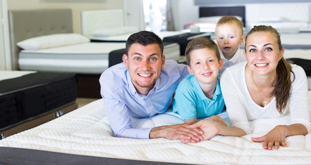 Young family of four are testing quality of mattress