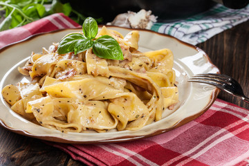 Pappardelle pasta with prosciutto and cheese sauce on a plate