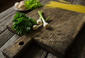 Fresh parsley, young garlig and pasta on a wooden board