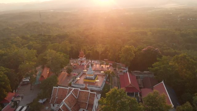 4k Aerial Drone shot above on top of Thai Buddhist temple  wat pagoda on top of the mountain, temple in the middle of forest , sunset golden hour, calm peaceful spiritual landmark. sun light