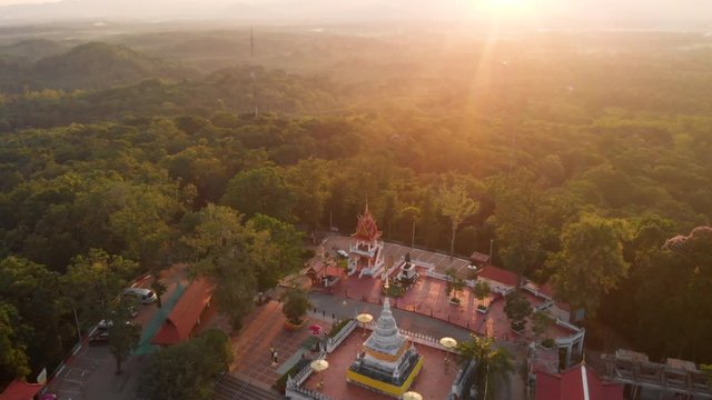 4k Aerial Drone shot dolly backward above Thai Buddhist temple pagoda on top of the mountain, Asia travel Journey, believer meditation, sunset golden hour, calm peaceful spiritual landmark. sun light