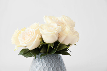 Vase with beautiful white roses on light background