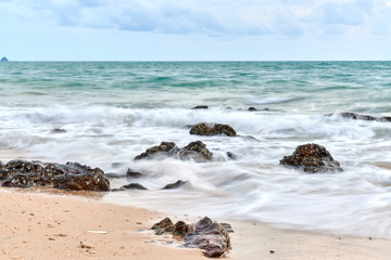 Fototapeta na wymiar a wavy sea with rocks near a beach.