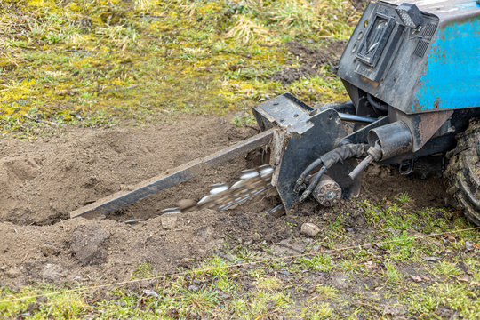 Industrial Earth Moving Machinery Digs A Row In The Soil For Optical Network Cable Connections