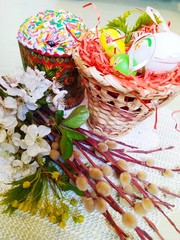 Easter still life basket with willow branches cherry blossom cake and painted eggs on a table