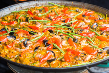 Closeup of delicious Seafood Paella cooking in a large frying pan. Traditional food and culinary seafood dish. 