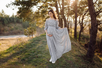 Young pregnant woman relaxing in park outdoors