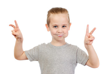 Young smiling caucasian boy with lollipop shows victory sign in mouth isolated on white background - 353064356