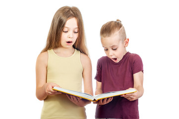 Young surprised cute girl and boy are looking at the yellow book isolated on white background - 353064739