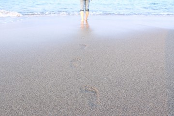 砂浜を歩く後ろ姿の女性
