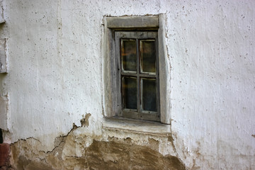 Fototapeta na wymiar An old cracked window frame in a white house in the village