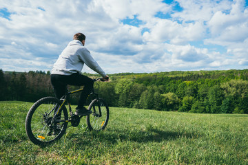 A man goes in for sports riding a mountain bike on a field in nature