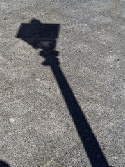 The shadow of an old city lantern on a granite pavement