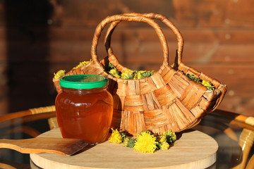 Dandelion Jelly and wooden basket of dandelion Flowers in the rays of the evening sun
