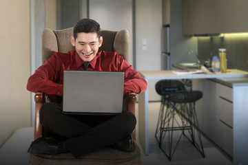 Asian businessman sitting and reading news on his laptop