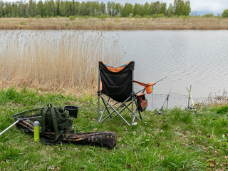 lake landscape with a fishing chair and fishing accessories on the lake shore
