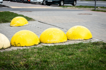 Yellow concrete spheres on the sidewalk, an obstacle to parking cars in the wrong place.