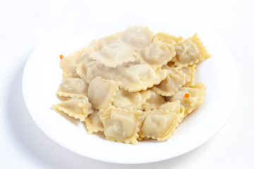 on white background. A plate of white color is round, several ravioli lie on it and steam comes. There is a shadow. Close-up