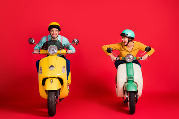 Portrait of nice attractive crazy overjoyed addicted cheerful cheery glad couple driving moped having fun rally race fast speed lovers isolated over bright vivid shine vibrant red color background