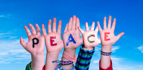 Children Hands Building Colorful English Word Peace. Blue Sky As Background