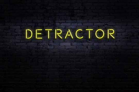 Night view of neon sign on brick wall with inscription detractor