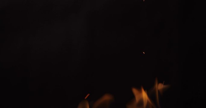 Sparkling, flying up sparkles for using in composition, vertical on black backdrop isolated. Screen mode for blending or transitions. Bright flames of fire on studio background, slow motion 50 fps 4k