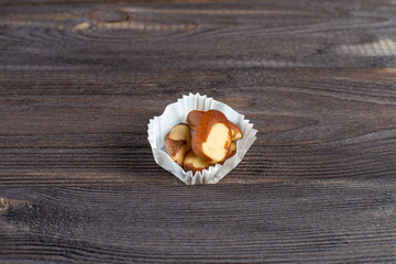 serving of brazil nuts in a paper muffin cup on a dark wood background