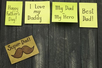 Stickers with greetings on the occasion of Father's Day on a dark wooden board