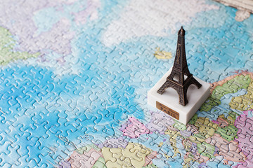 Tourist attractions and souvenir Eiffel tower metal model Paris France on world map background of puzzles for travelers. Copy space
