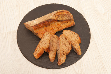 French buckwheat long loaf sliced into pieces on a graphite round board