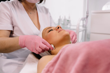 Obraz na płótnie Canvas Beautiful woman having a facial in a beauty salon lying with her eyes closed in relaxation and enjoyment as the beautician cleanses her skin