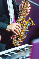 Musical instrument saxophone close-up. Hands on a musical instrument.