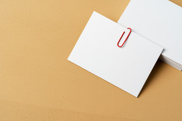 Pile of white businesscards with a clip on beige background