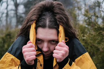 Girl traveller wearing yellow jacket and hiding head from rain