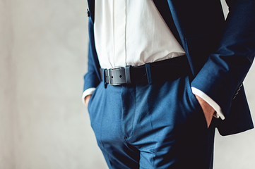 close up part of man body in blue suit with hands in pockets on white background
