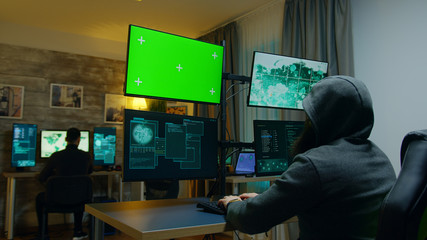 Team of hackers making a dangerous virus for cybercrime. Computer with green screen.