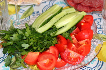Tomatoes, cucumbers and greens on a glass plate