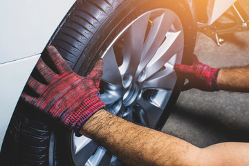 The mechanic's hand holding alloy wheel for changing alloy wheel into the wheel hub at car tire shop.