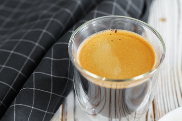 Glass cup of coffee on wooden kitchen table