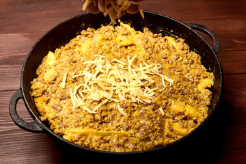 raw casseroles of potatoes and minced meat with cheese in a pan.