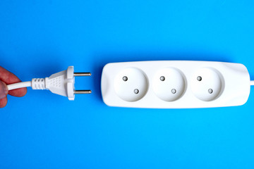 Electrical extension cord, plug and socket on a blue background. The concept of work on electrification.