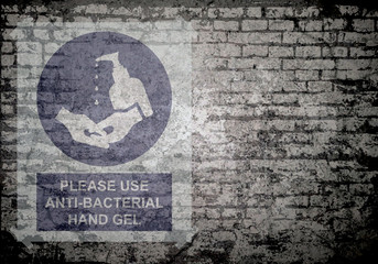 Grunge decayed faded brick wall background with please use anti bacterial hand gel sign to stop the spread of the worldwide pandemic