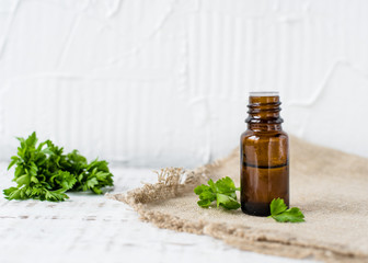 aroma Parsley oil in a dark glass bottle on a wooden table and natural green background