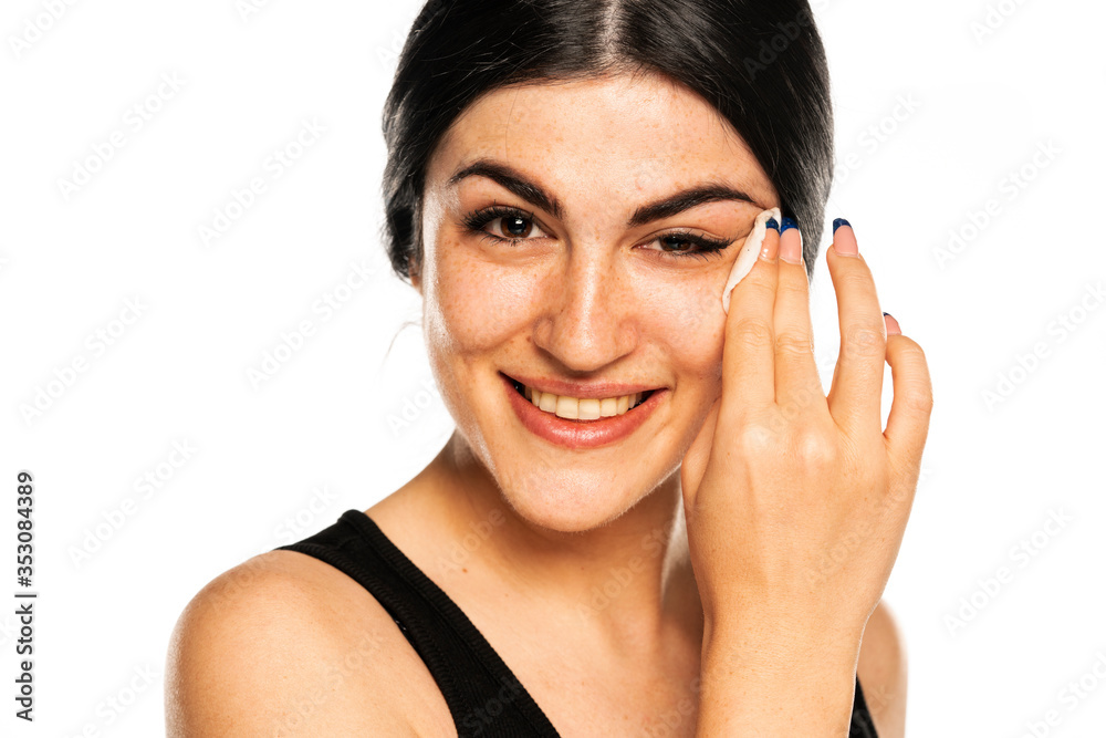 Wall mural happy young woman removes makeup with a cotton pad